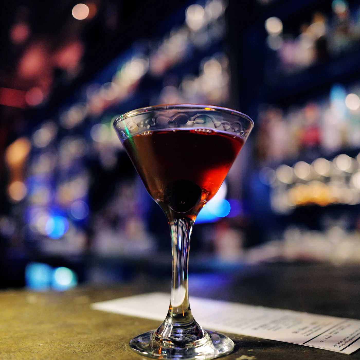 A dark cocktail with a cherry