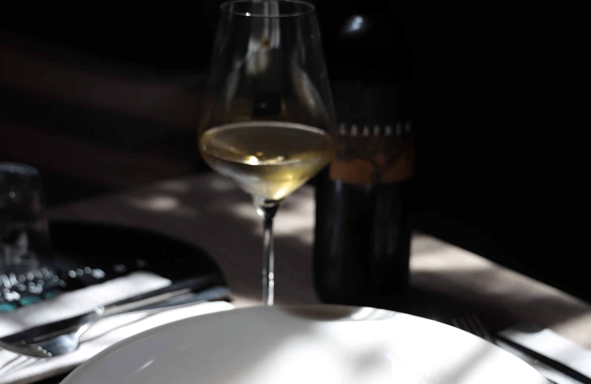 A plated dish and a glass of wine by candlelight