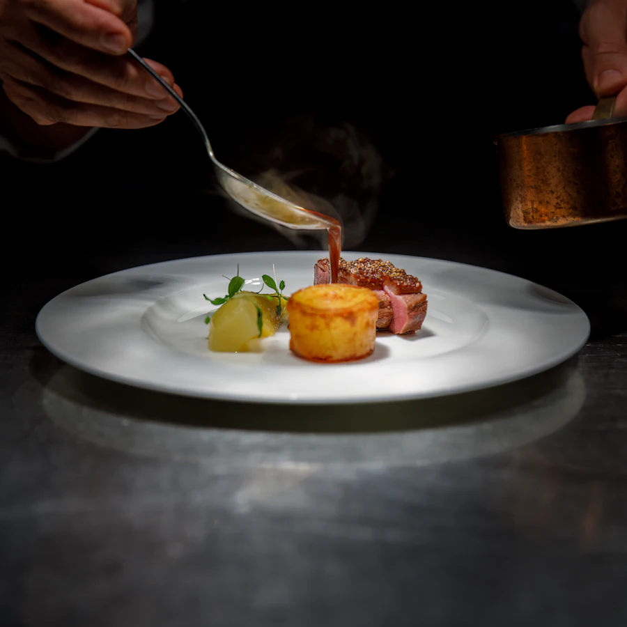 Sauce being poured over a plated steak